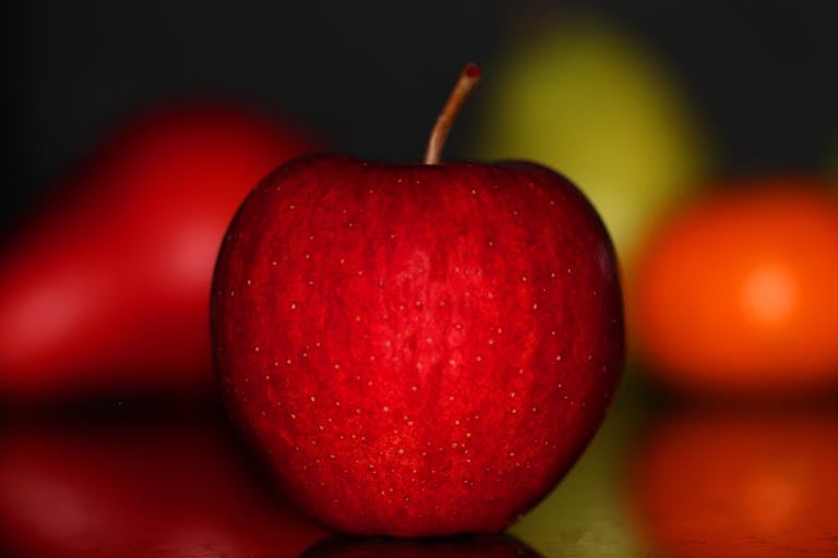 A crisp red apple with a glossy surface and soft background, capturing freshness.